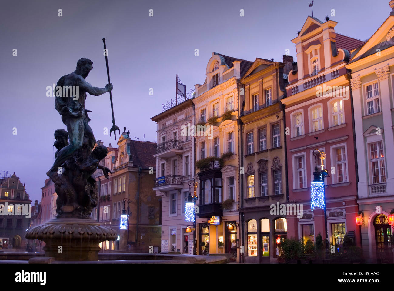 Una estatua de Neptuno sosteniendo una lanza se asienta en una fuente en la Plaza del Mercado Viejo (Stary Rynek) al atardecer, Poznan, Polonia Foto de stock