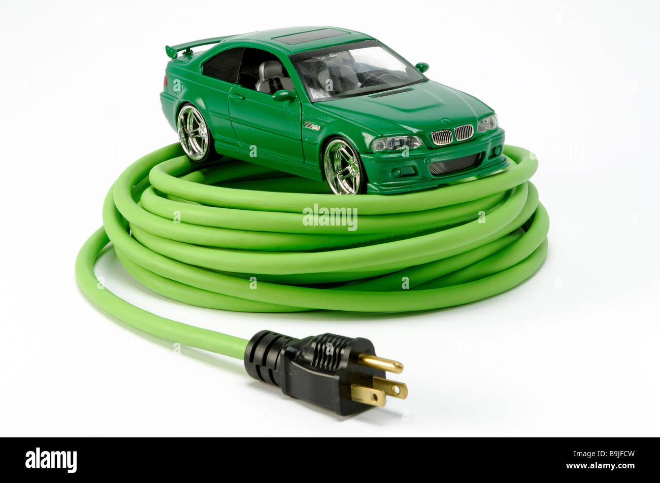 Un coche en un automóvil verde verde extensión eléctrica en espiral con un enchufe del cable de alimentación Foto de stock