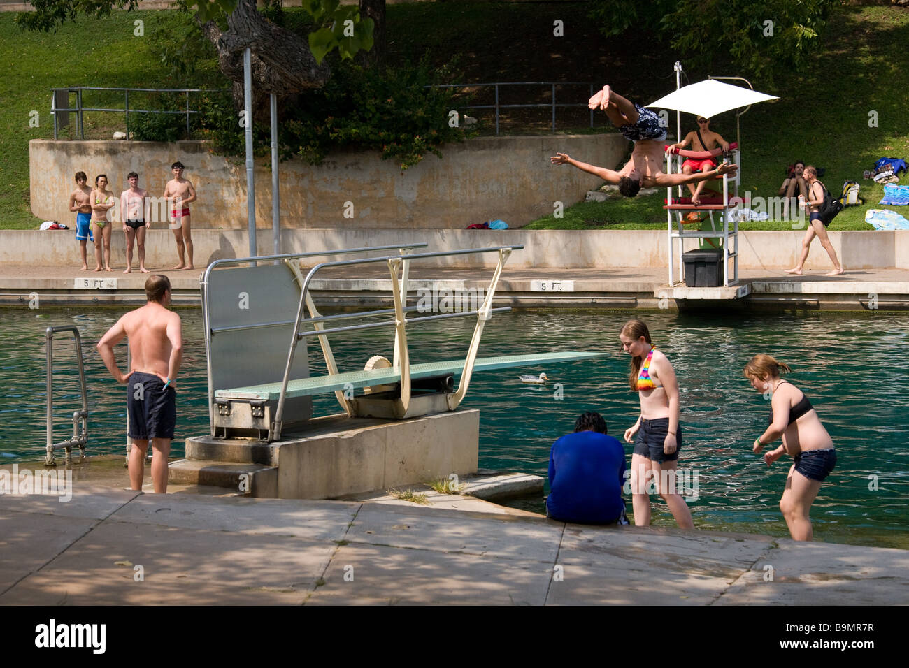 Austin, Texas - un niño se voltea el trampolín como bañistas miran a la piscina Barton Springs Pool Foto de stock
