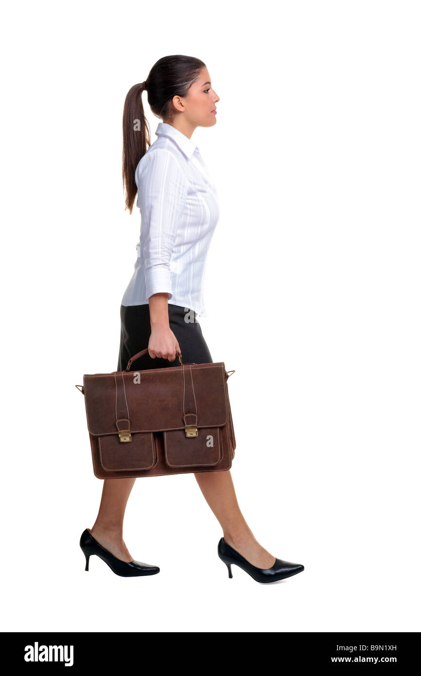 Atractiva joven empresaria caminando por llevar un maletín de cuero marrón aislado sobre fondo blanco. Foto de stock