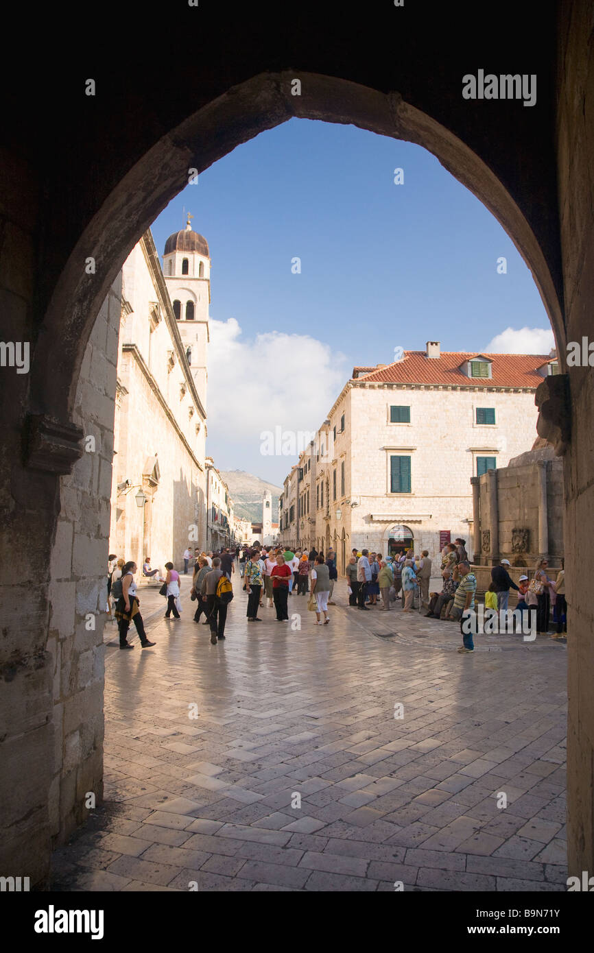 Vista a través de la Puerta Pile con turistas y visitantes paseando por la plaza Stradun en la ciudad amurallada de Dubrovnik Croacia Foto de stock