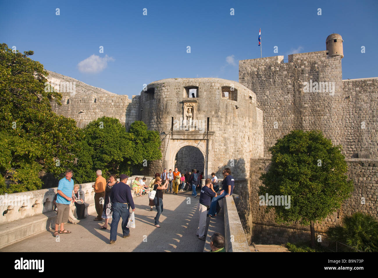 Turistas y visitantes pasear fuera aunque la Puerta Pile en la ciudad amurallada de Dubrovnik en verano Sol Costa Dálmata Cro Foto de stock
