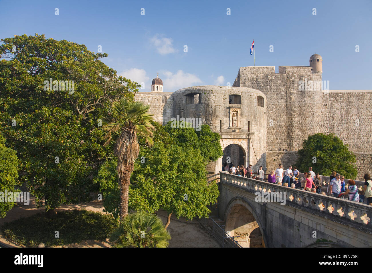 Turistas y visitantes pasear fuera aunque la Puerta Pile en la ciudad amurallada de Dubrovnik en verano Sol Costa Dálmata Cro Foto de stock