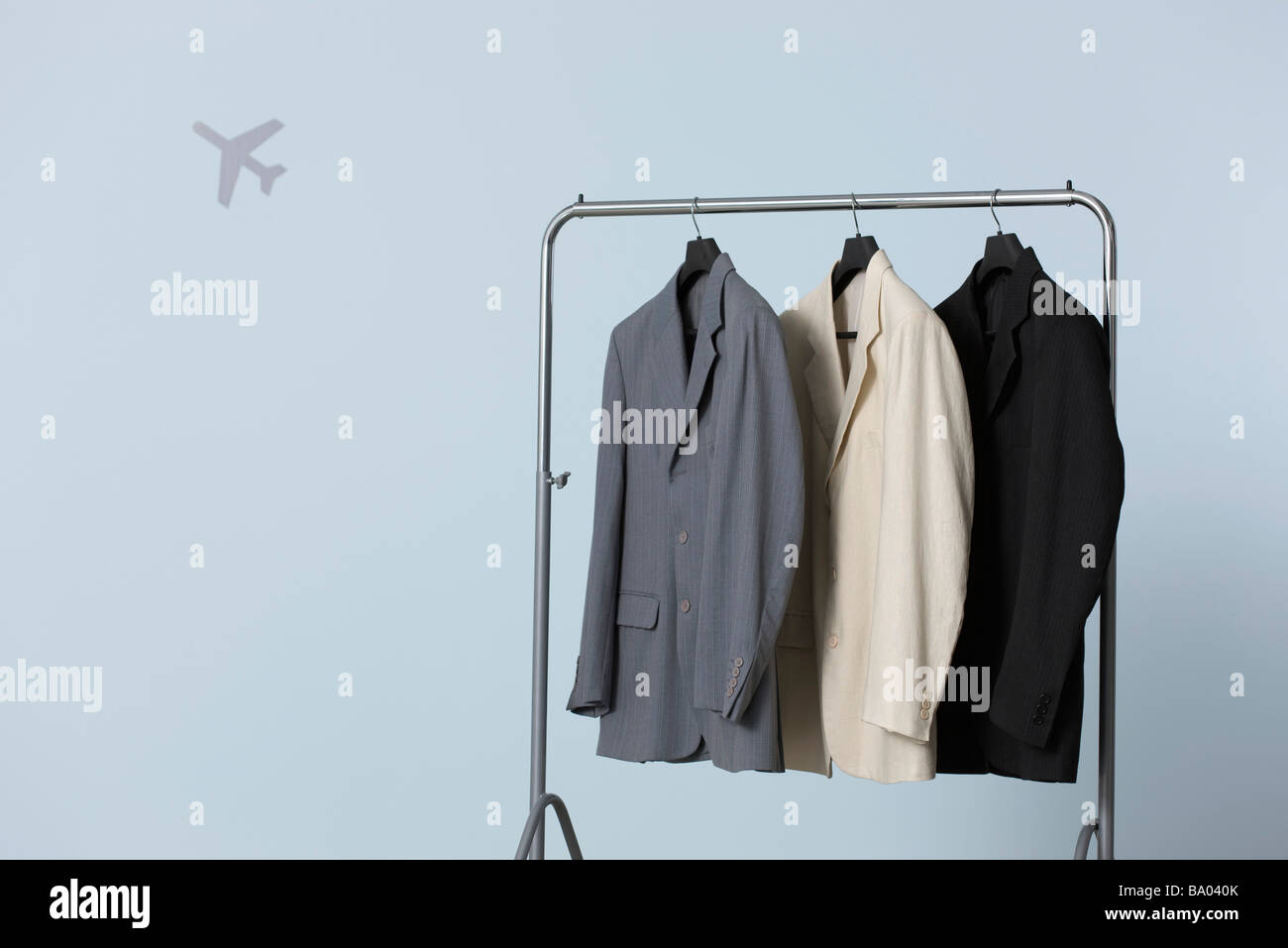 Tres hombres de traje chaqueta colgando en el perchero, forma de avión en  segundo plano Fotografía de stock - Alamy