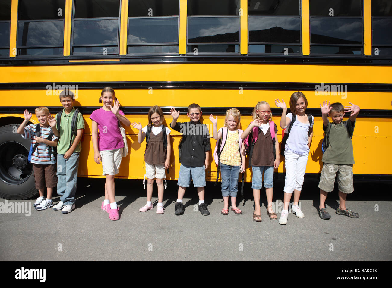 Grupo de niños de escuela en la parte delantera del autobús escolar Foto de stock