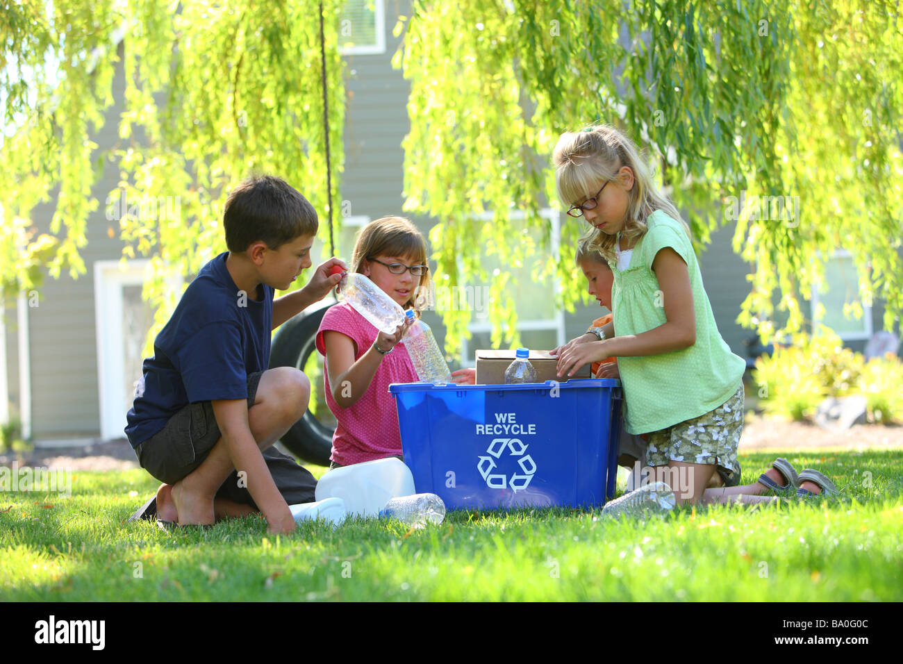 Grupo de niños al aire libre con papelera de reciclaje Foto de stock