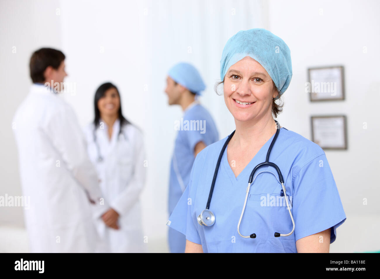 Retrato de enfermera con otro personal médico en segundo plano. Foto de stock