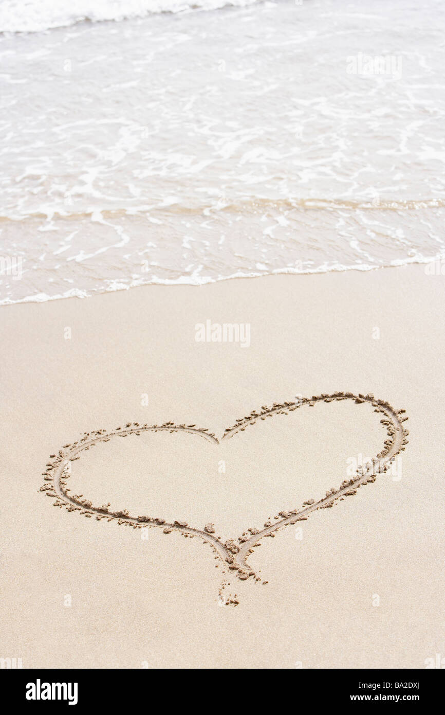 Forma corazón dibujado en la arena de la playa Foto de stock