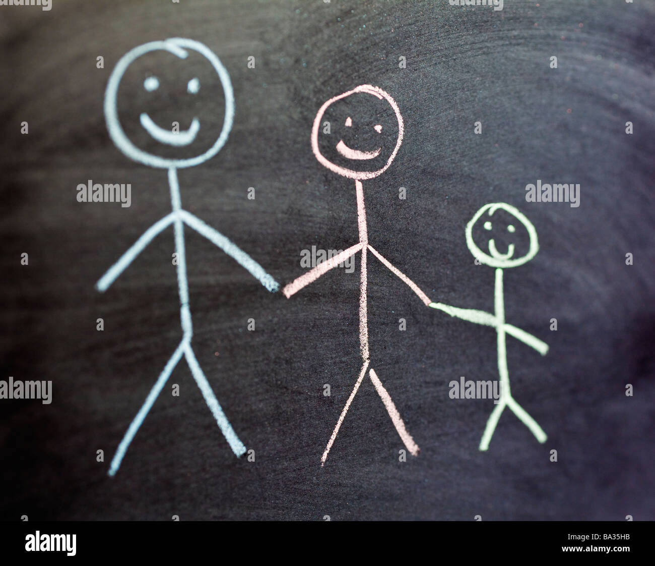 Dibujo de tiza de dos adultos y un niño de familia en color en una pizarra de cerca el enfoque selectivo Foto de stock