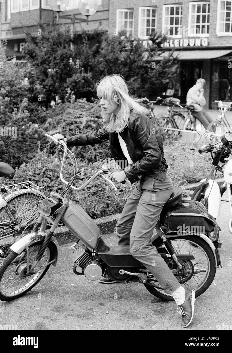 80, fotografía en blanco y negro, gente joven que estaba sentada en un pequeño ciclomotor, un joven en el fondo la cuida, chaqueta de cuero, pantalones, entre 14 y 17 años de edad Foto de stock