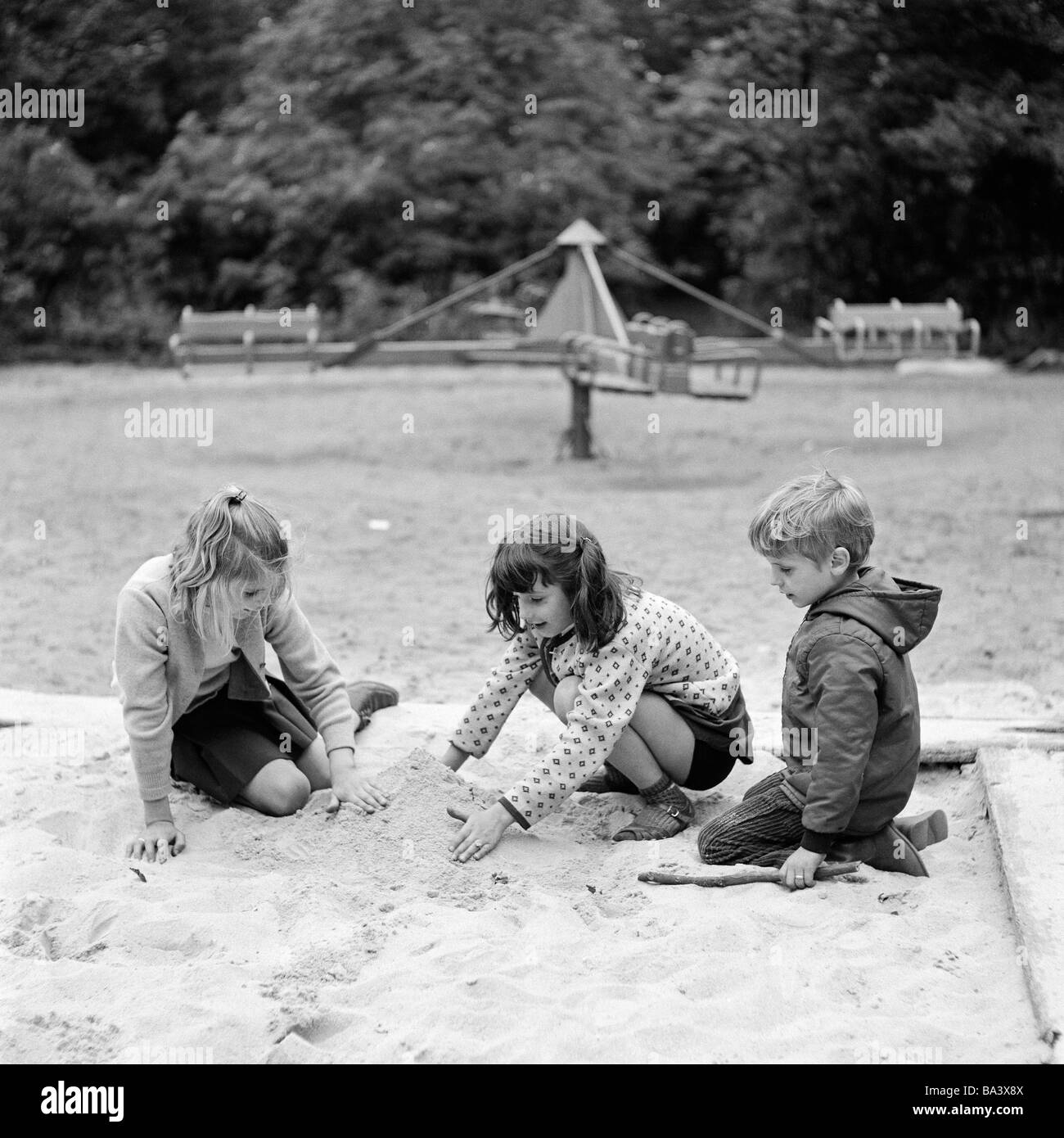 70, fotografía en blanco y negro, gente, niños, dos niñas y un niño jugando  en un sandbox, juegos para niños, con edades de 4 a 6 años Fotografía de  stock - Alamy