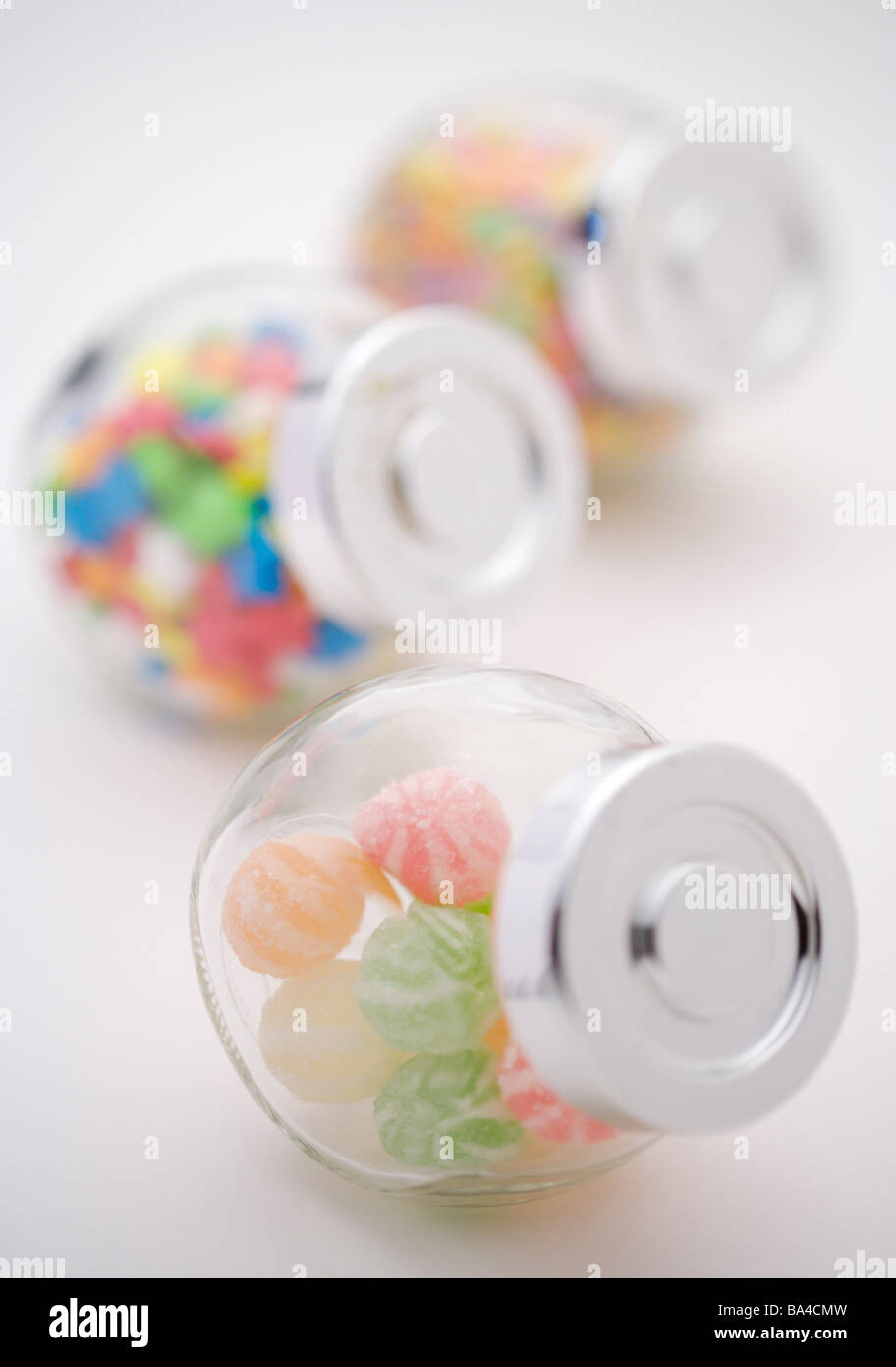 Caramelos de colores en frascos de vidrio en una fila Foto de stock