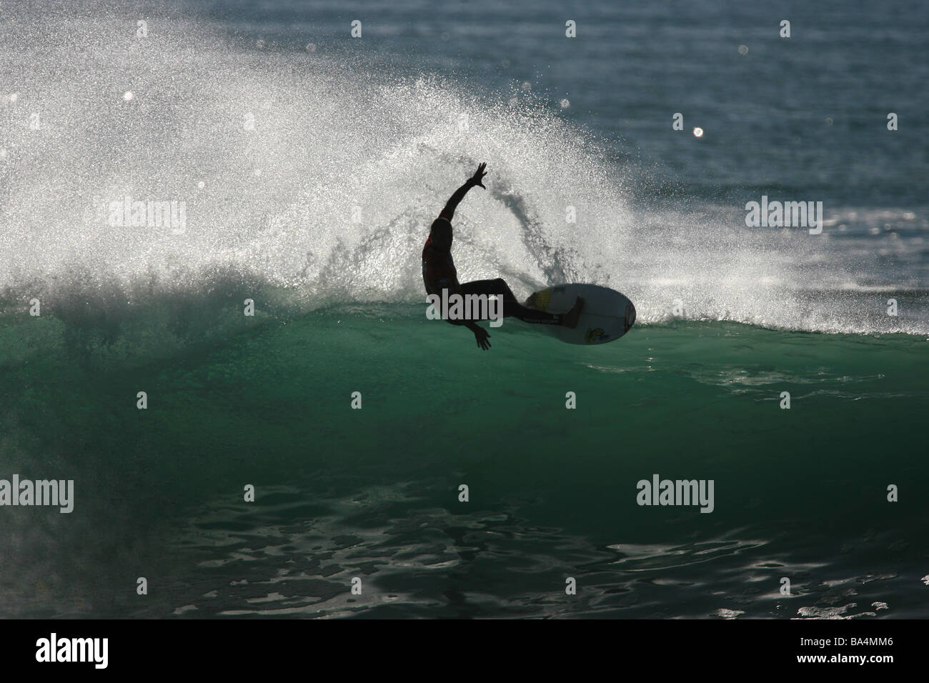Silueta de un surfista cabalgando una ola. Foto de stock