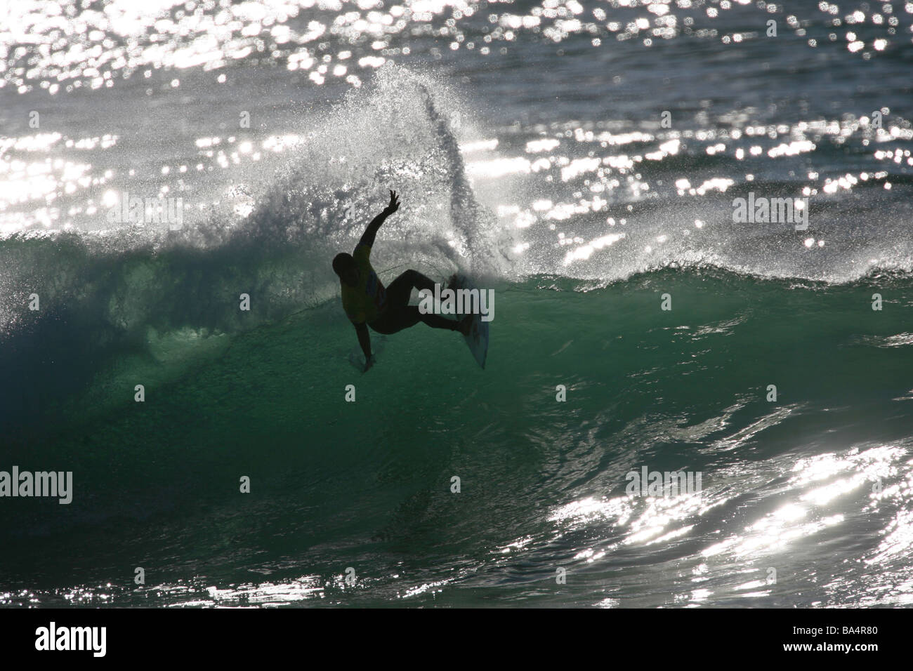 Silueta de un surfista cabalgando una ola. Foto de stock