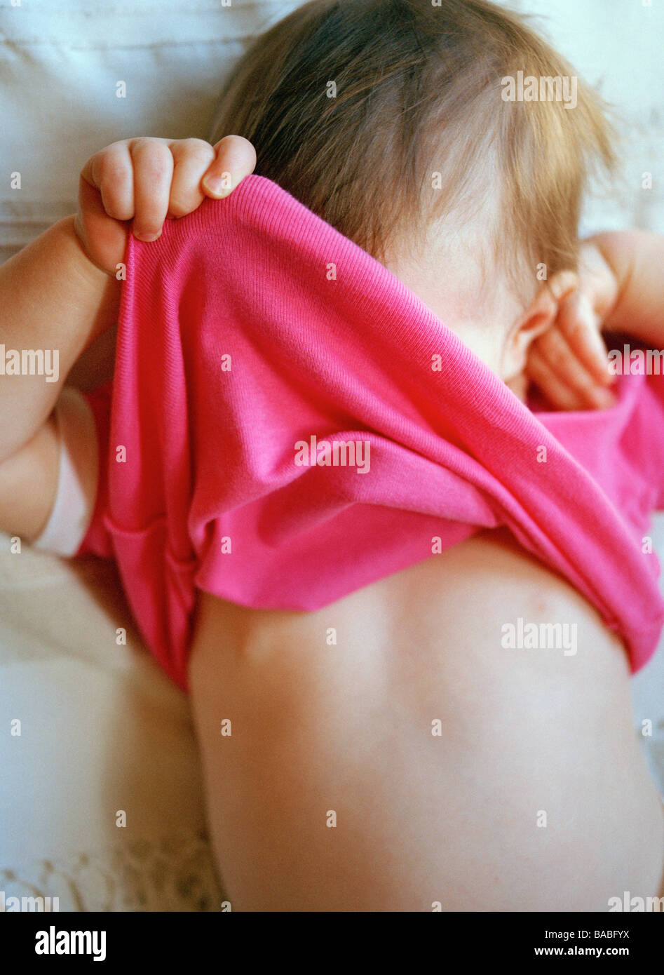 Una niña que se oculta detrás de su t-shirt Foto de stock