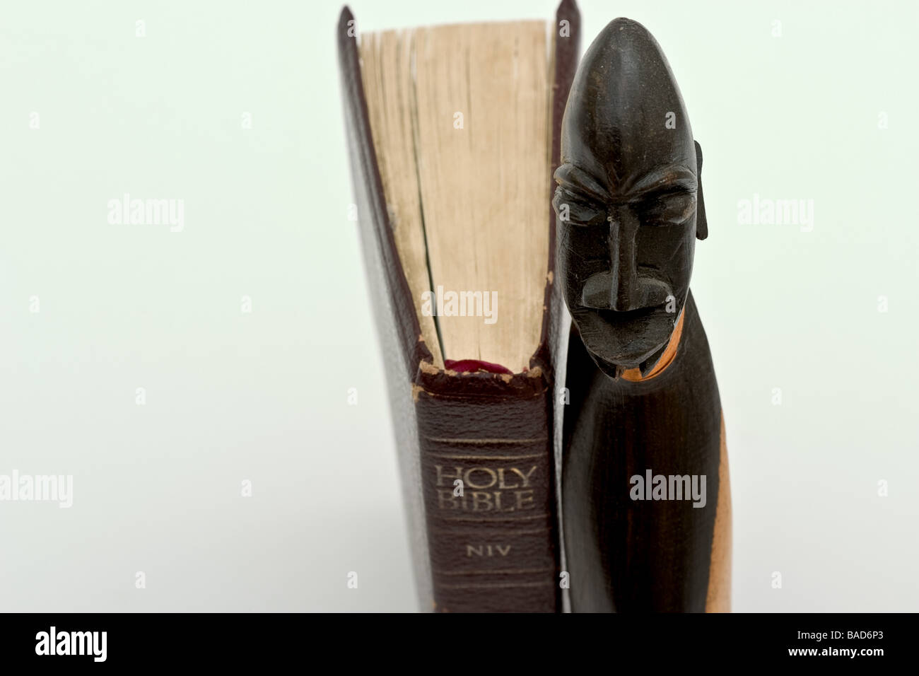 Pequeña estatuilla de madera Sudanés de pie junto a una biblia encuadernada de cuero Foto de stock