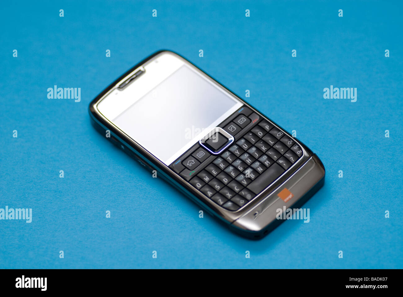 Teléfono móvil Nokia E71 con teclado QWERTY contra un fondo azul. Foto de stock