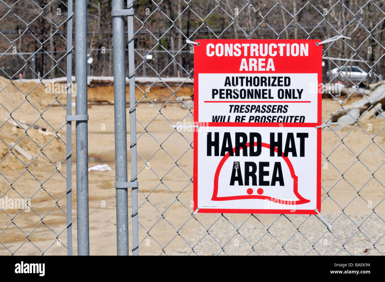 Señal de advertencia de sitio de construcción hard hat únicamente personal autorizado de área intrusos serán procesados en un eslabón de la cadena cerco Foto de stock