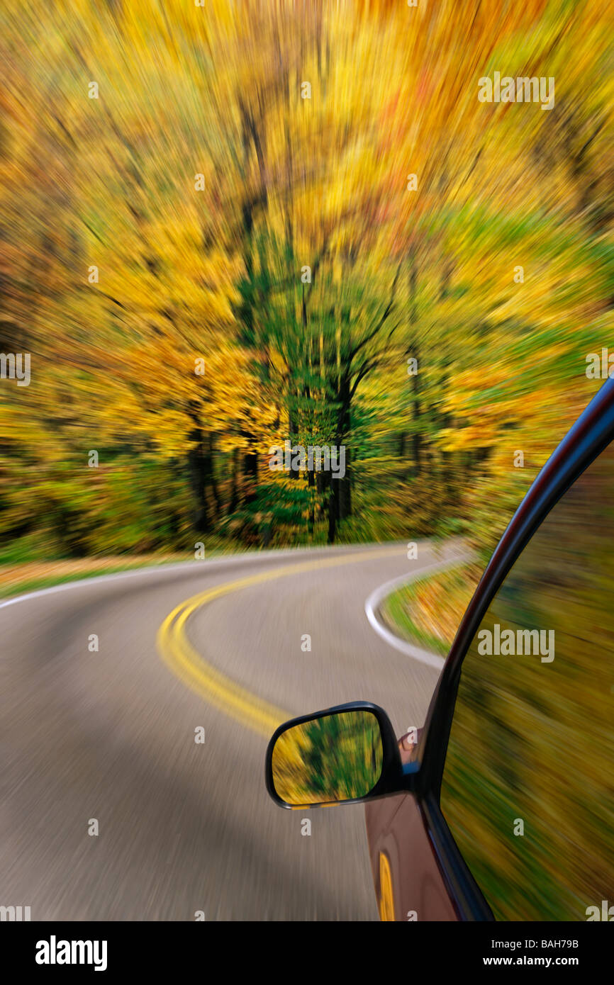 Automóvil conducir por una carretera rural con los colores del otoño y afectar borrosa Foto de stock
