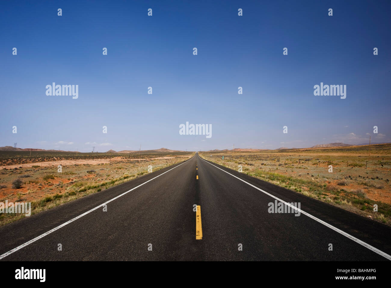 Carretera asfaltada que llega recto por millas hasta el horizonte Foto de stock