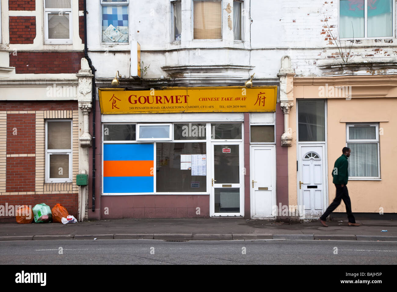Hombre caminando pasado chino quitarle tienda en correr por zona de Cardiff, Gales, Reino Unido Foto de stock