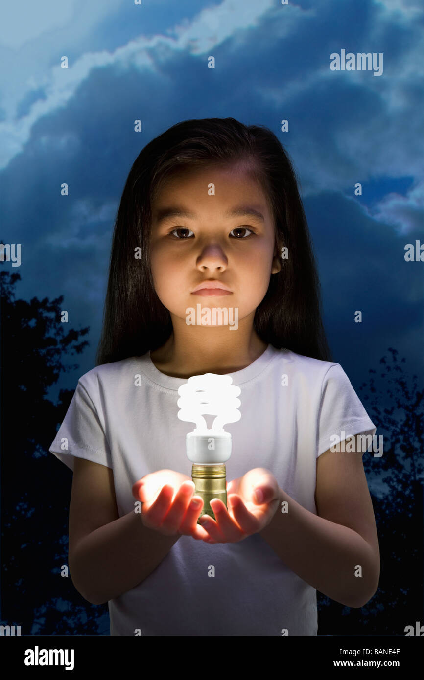 Niña China mantiene Brillante bombilla CFL Foto de stock