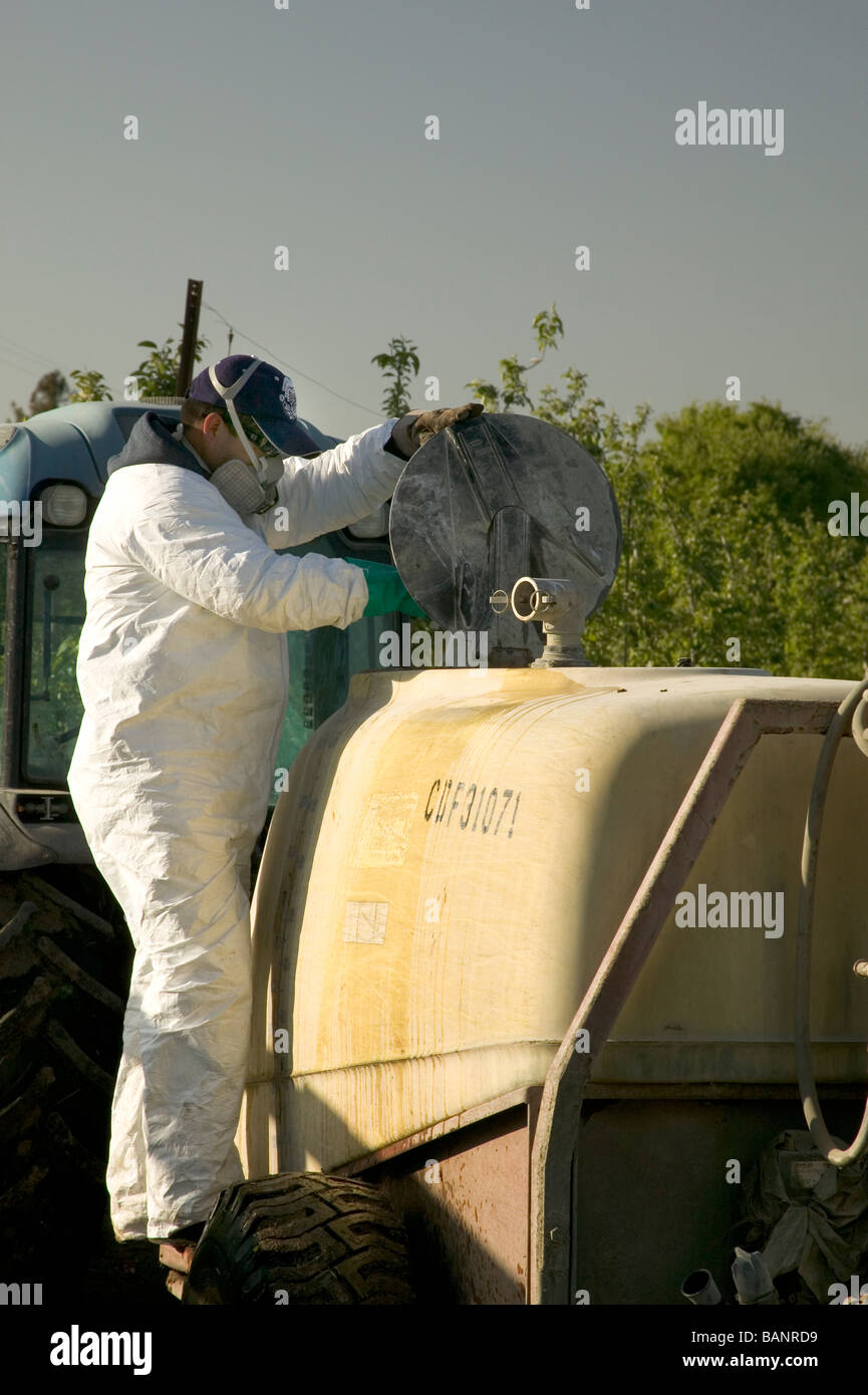 La adición de productos químicos en aerosol agricultor rig vistiendo ropa protectora. Foto de stock