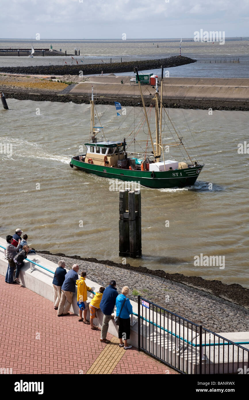 Barco de pesca entrando en puerto vigilado por turistas Harlingen Frisia Holanda Foto de stock