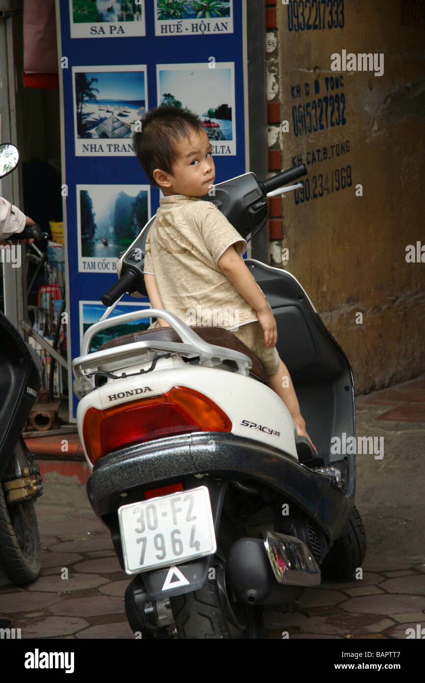 Un joven pretende conducir una moto Honda por sí mismo fuera de su casa, en Hanoi, Vietnam Foto de stock