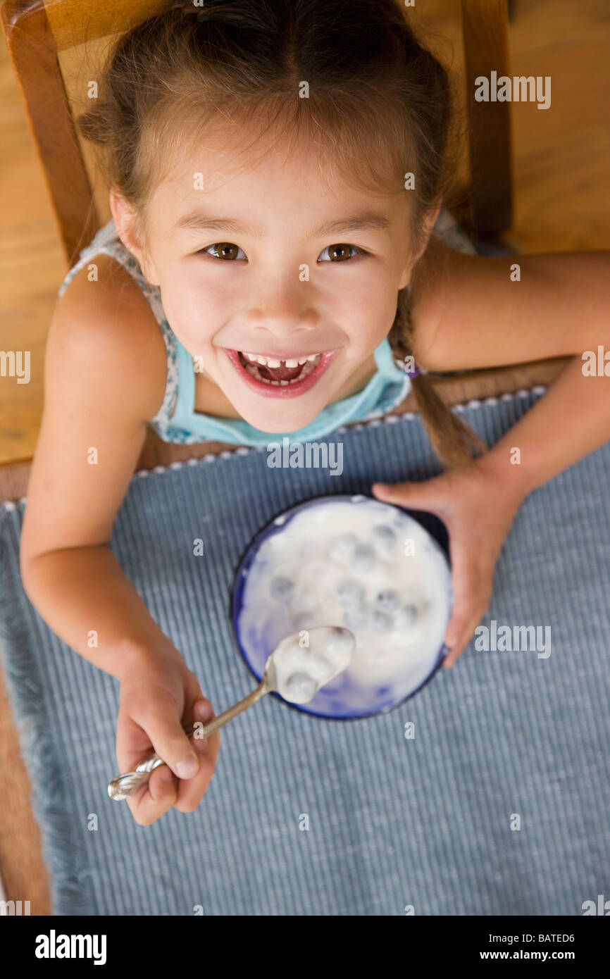 Joven de raza mixta consumir yogur con una cuchara Foto de stock