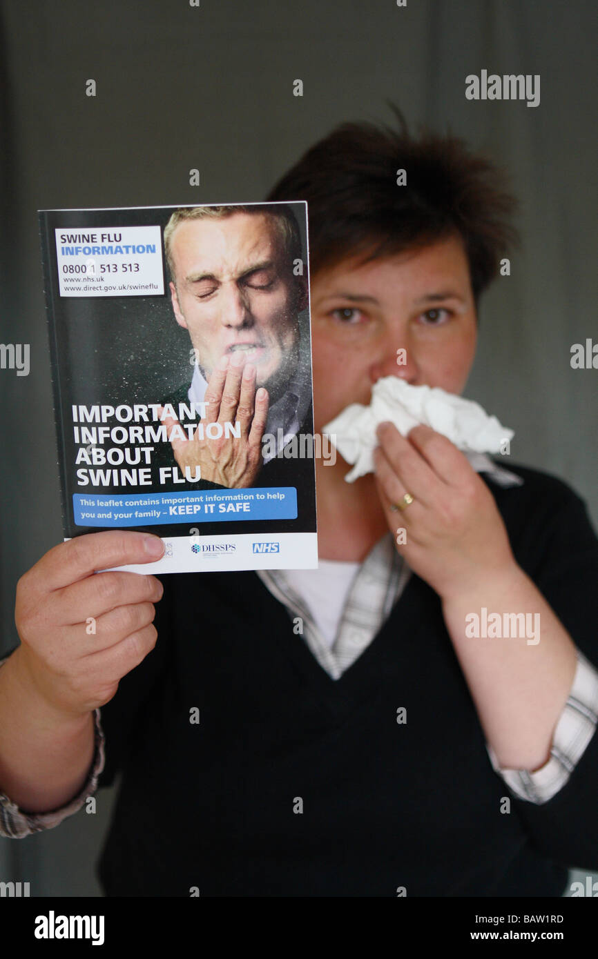 La gripe porcina mujer con pañuelo de papel barrido nariz sosteniendo el Gobierno británico la gripe porcina folleto informativo folleto folleto Foto de stock