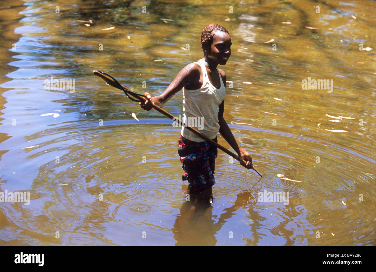 Joven chica Aborigional pesca con arpón en el río Coen, Queensland