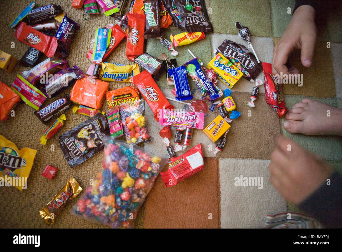 Un niño escanciar candy tuvo para con la tradición del truco o trato en la noche de Halloween, en casa, en el suelo, haciendo una selección Foto de stock