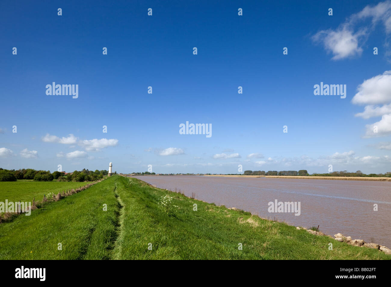 El banco del río en el río Ouse, East Yorkshire, Inglaterra, Reino Unido mostrando el dique de prevención de inundaciones y el faro en el Whitgift Foto de stock