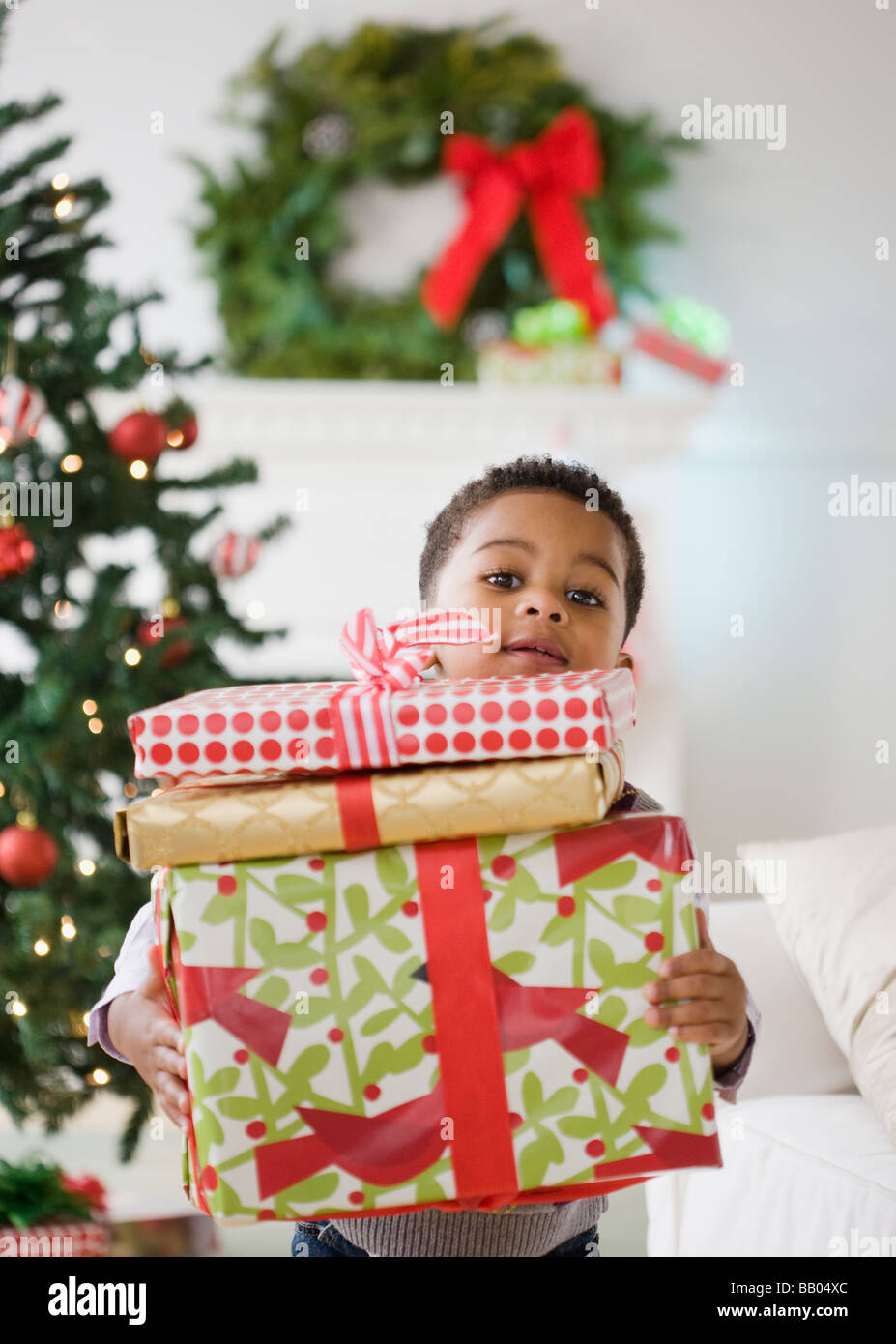 Afroamericanos niño sosteniendo la pila de regalos de Navidad Foto de stock