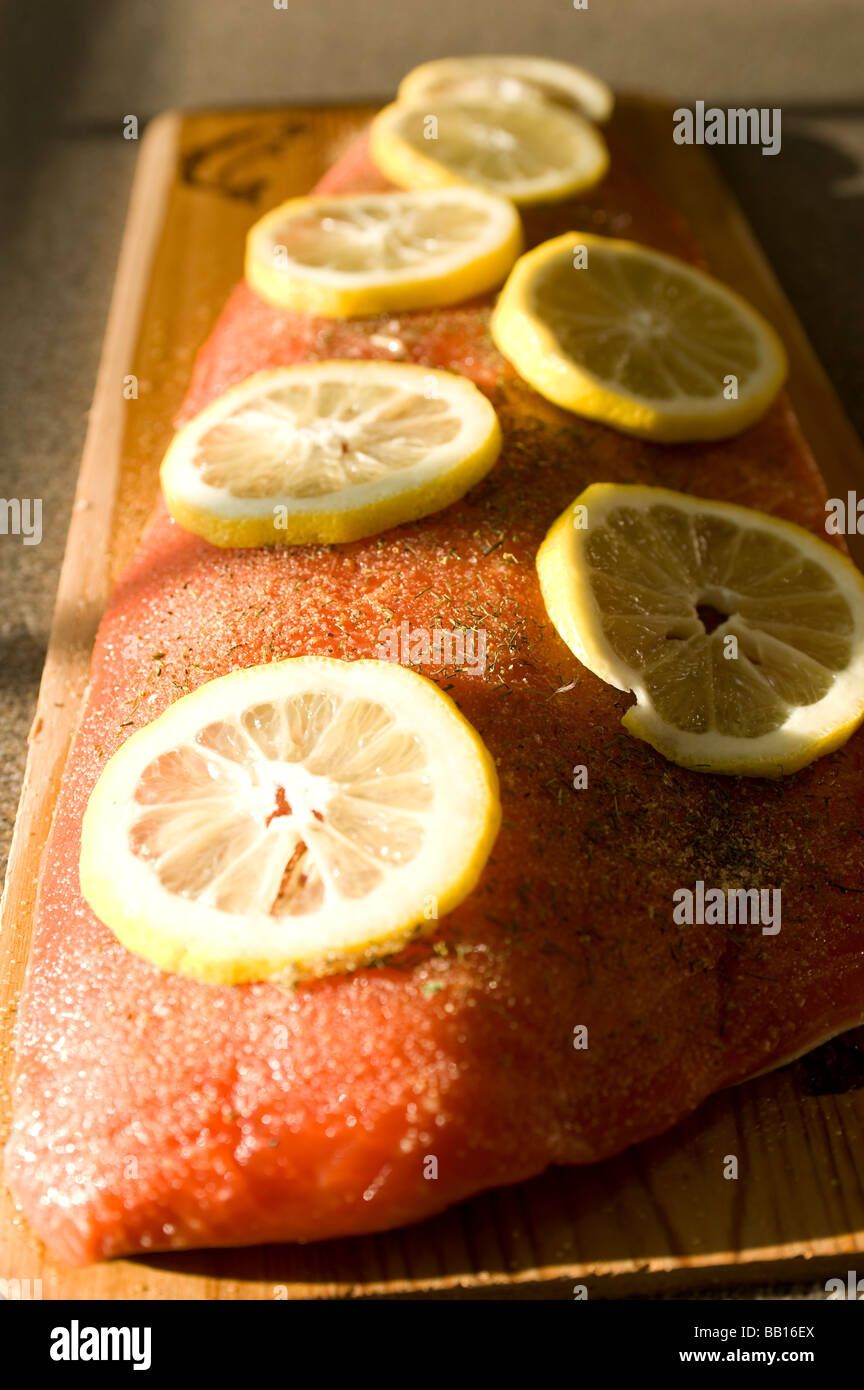 Un filete de salmón sockeye es retratada en una tabla de cedro empapado de agua en que se cocinan en una parrilla Foto de stock