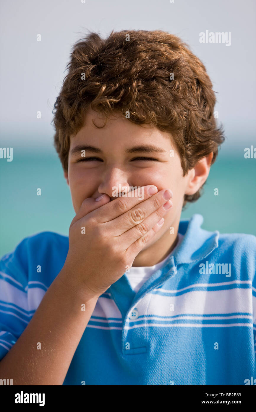 Retrato de un niño sonriendo con la boca cubierta Foto de stock