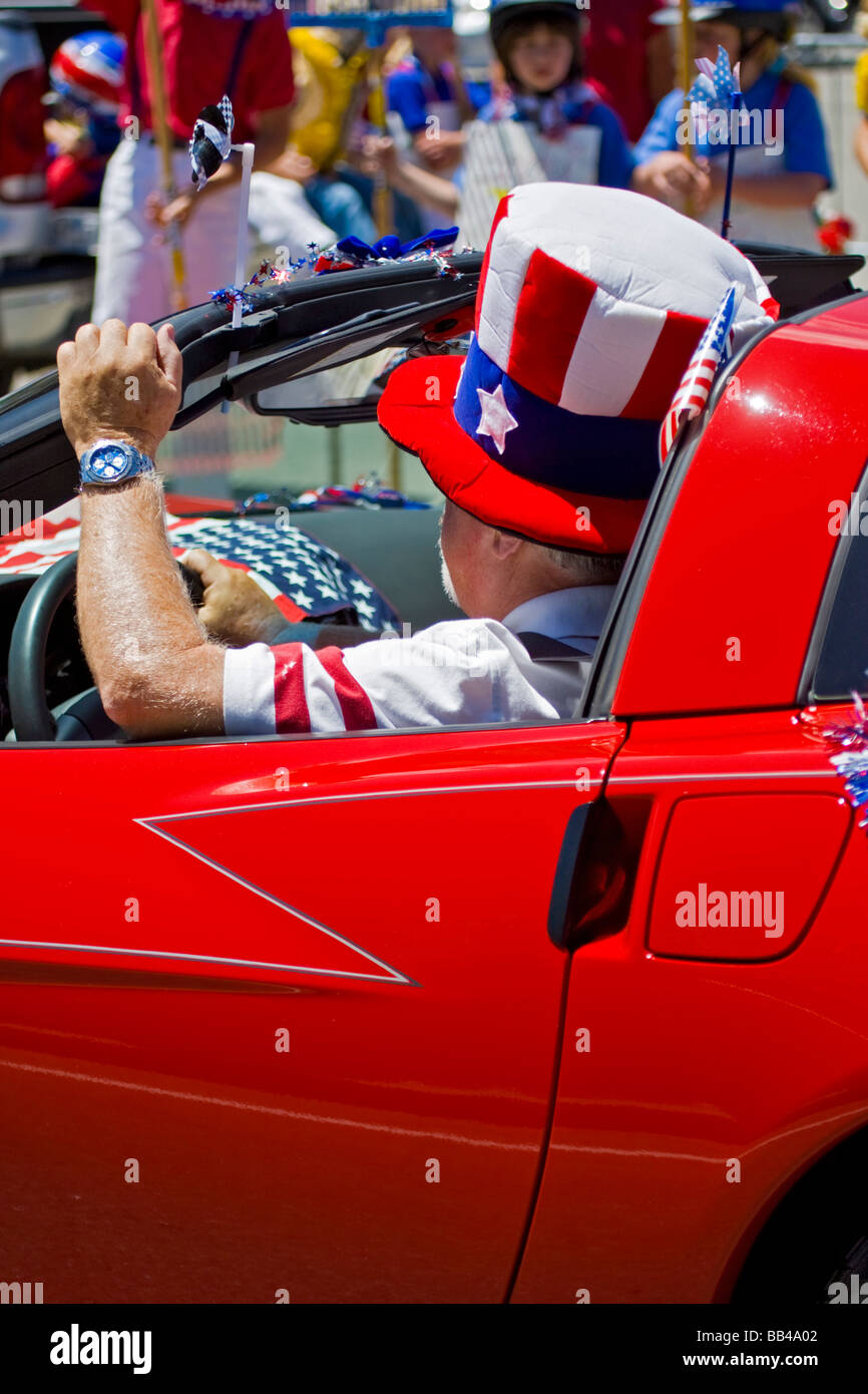Frisco, Colorado, EE.UU. Hombre conduce coche rojo vistiendo el Tío Sam hat en julio cuarto desfile. Foto de stock
