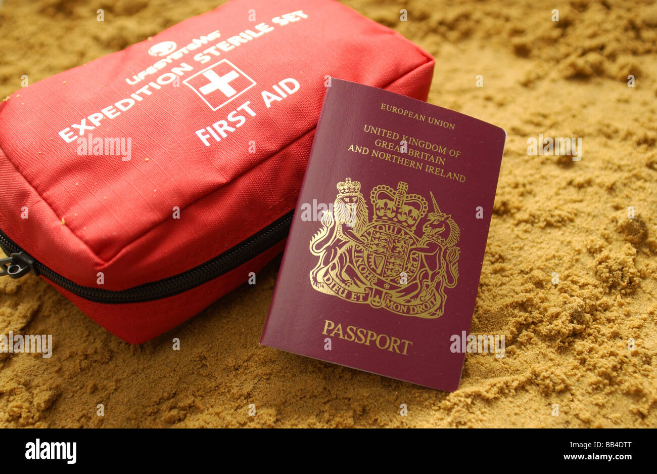 Un pasaporte en una playa con un kit de primeros auxilios de viaje Foto de stock