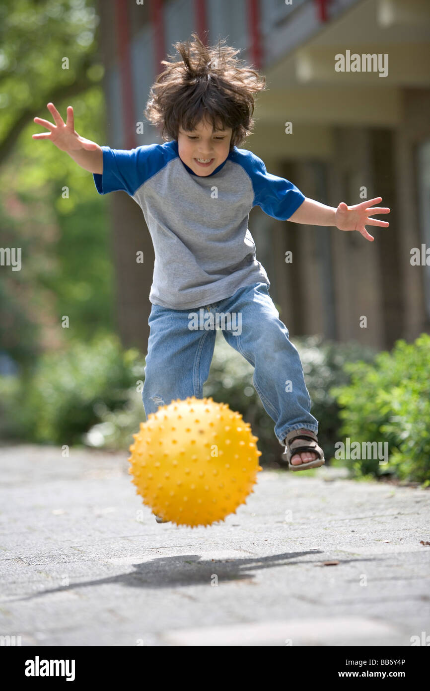 Niñito pateando una bola amarilla Foto de stock