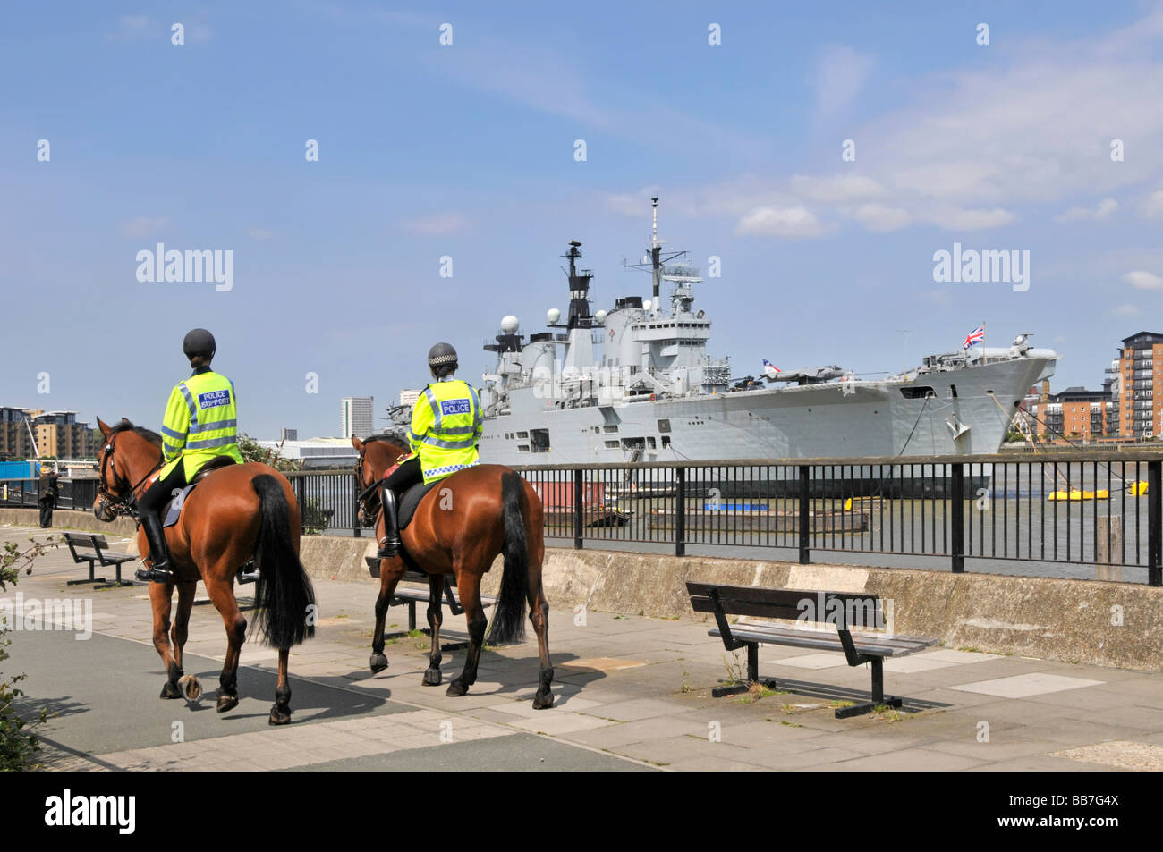 Royal Navy acorazado HMS Ilustre luz portaaviones amarrado en el río Támesis de Londres Greenwich pasando de patrulla de la policía montada Foto de stock