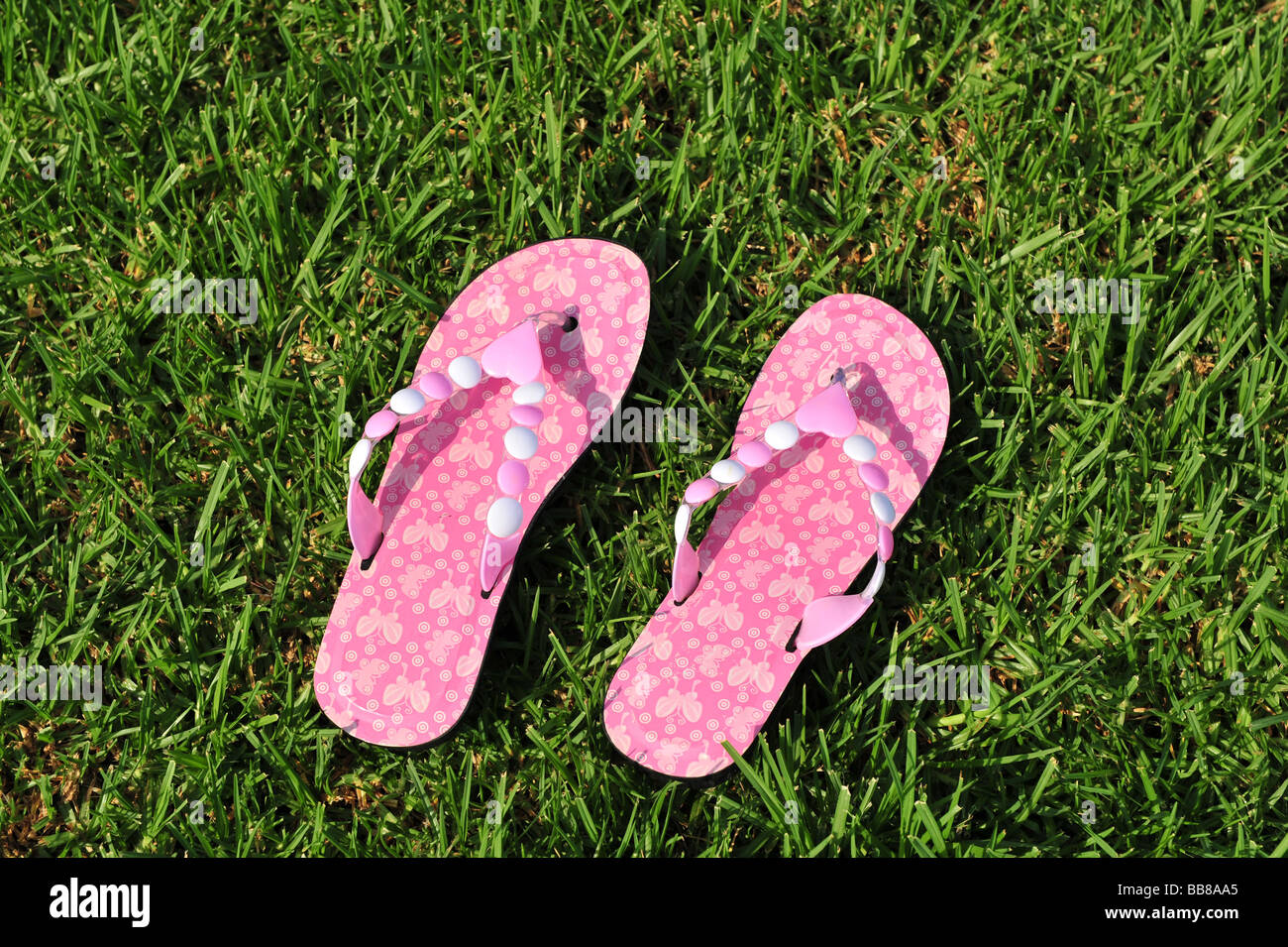 Par de womens rosa flip flop sandalias en pasto verde Fotograf a