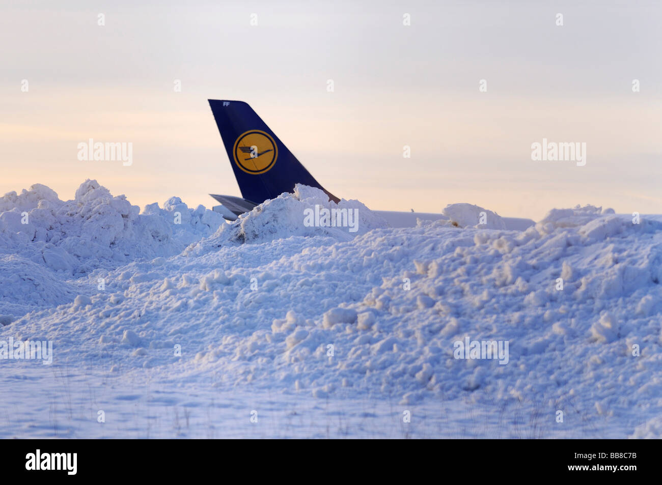 Lufthansa aleta de cola detrás de los montículos de nieve al lado de una pista Foto de stock