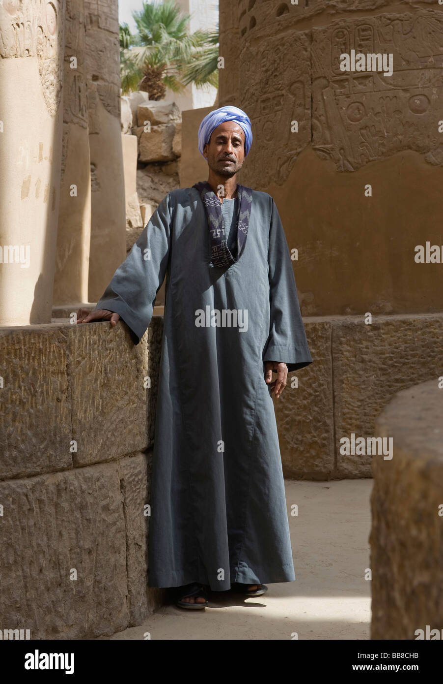 Hombre nubio vestido con ropa tradicional, de pie entre columnas, Karnak Templo, Luxor, Egipto, África Foto de stock