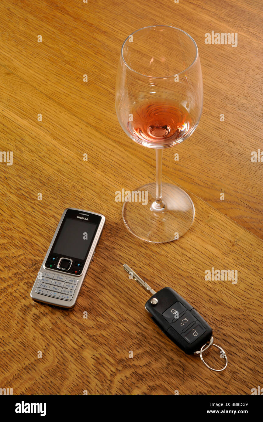 Vaciar vaso de vino tinto, las llaves del coche, simbólica de la conducción bajo los efectos del alcohol. Foto de stock