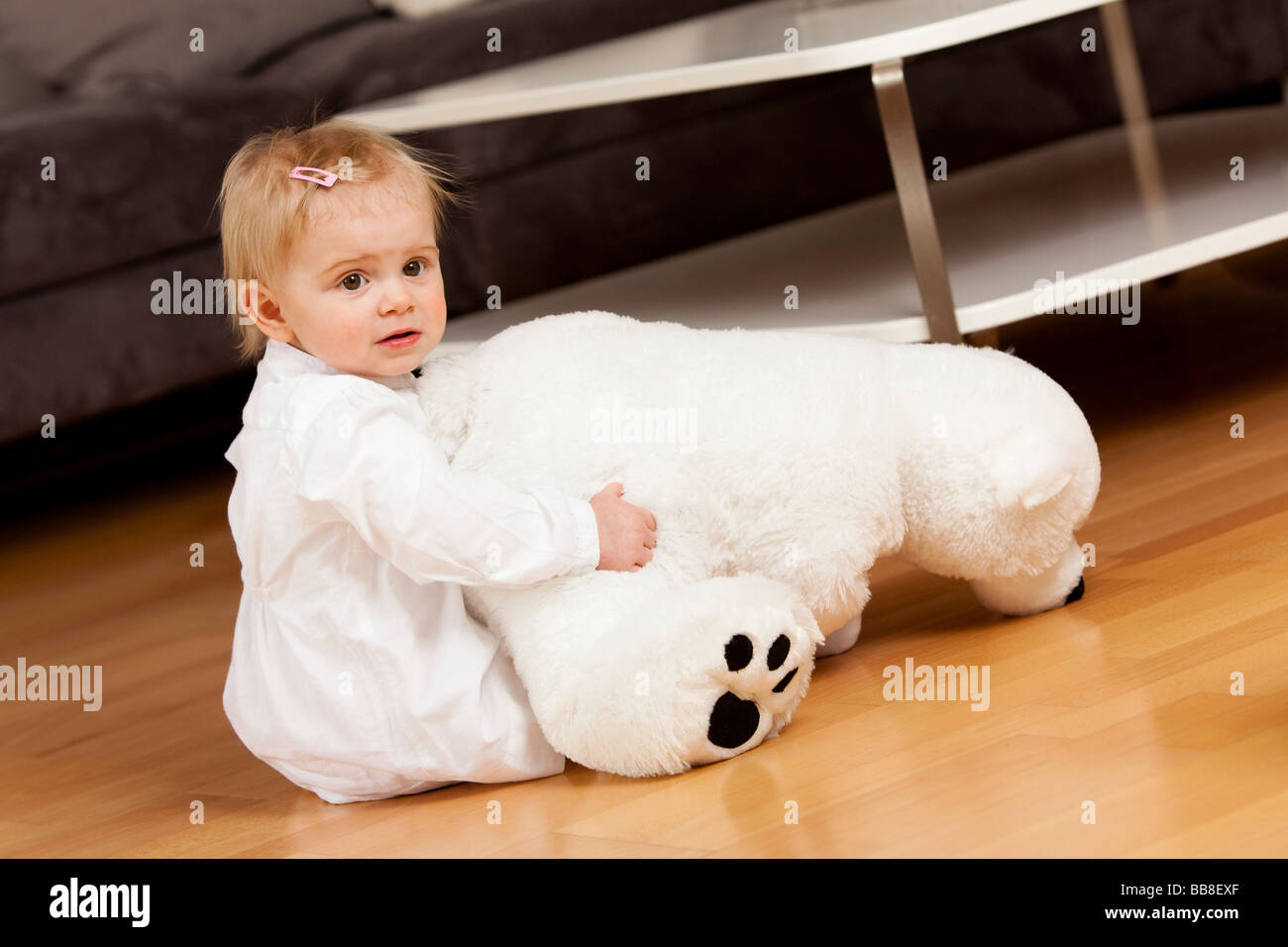 Niña de 1 años, jugando en el piso con un oso polar de juguete Foto de stock