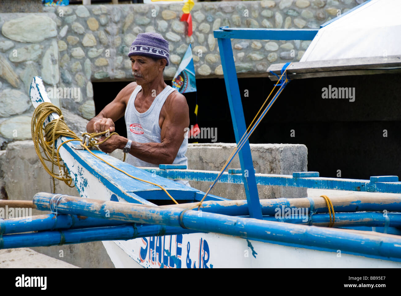 Barquero preparando su barco bangka (filipino) en Puerto Galera, Filipinas Foto de stock