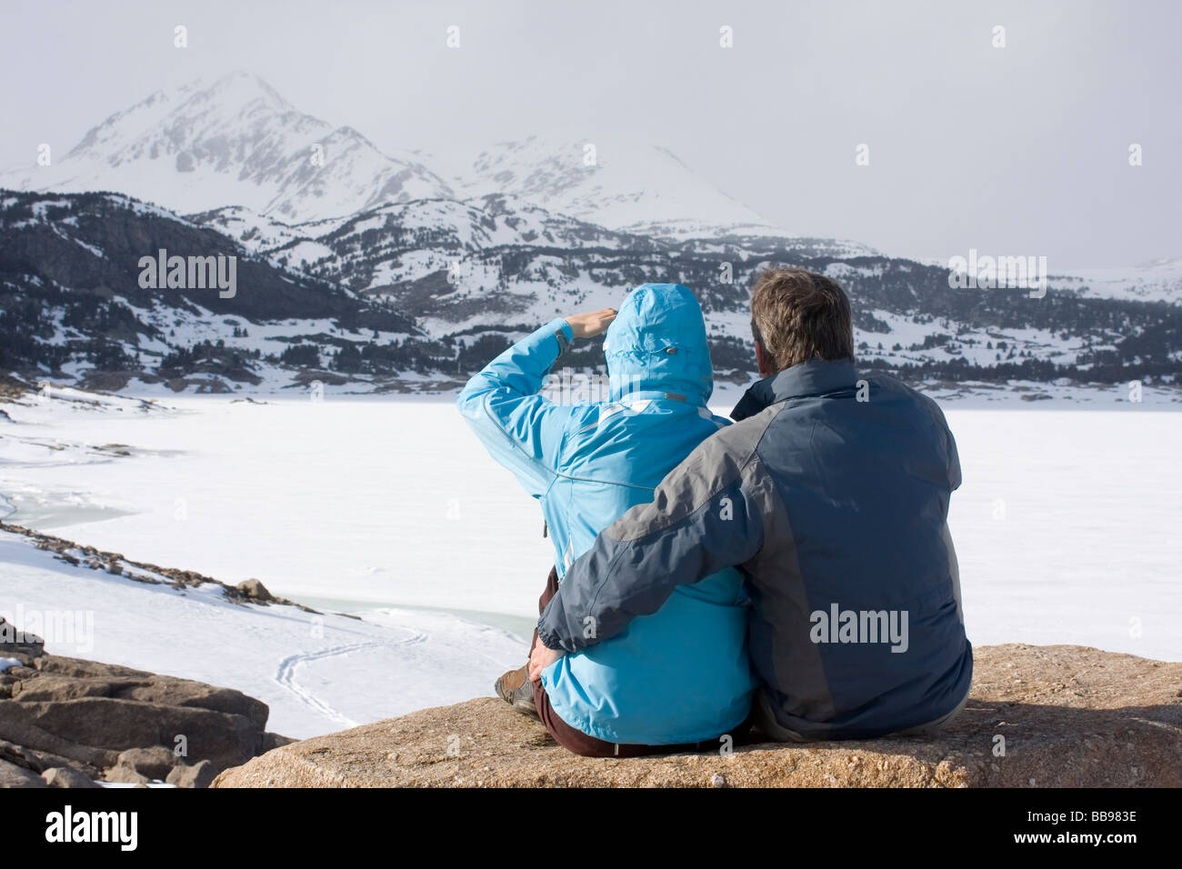 Pareja sentada delante de las montañas con nieve y hielo Foto de stock
