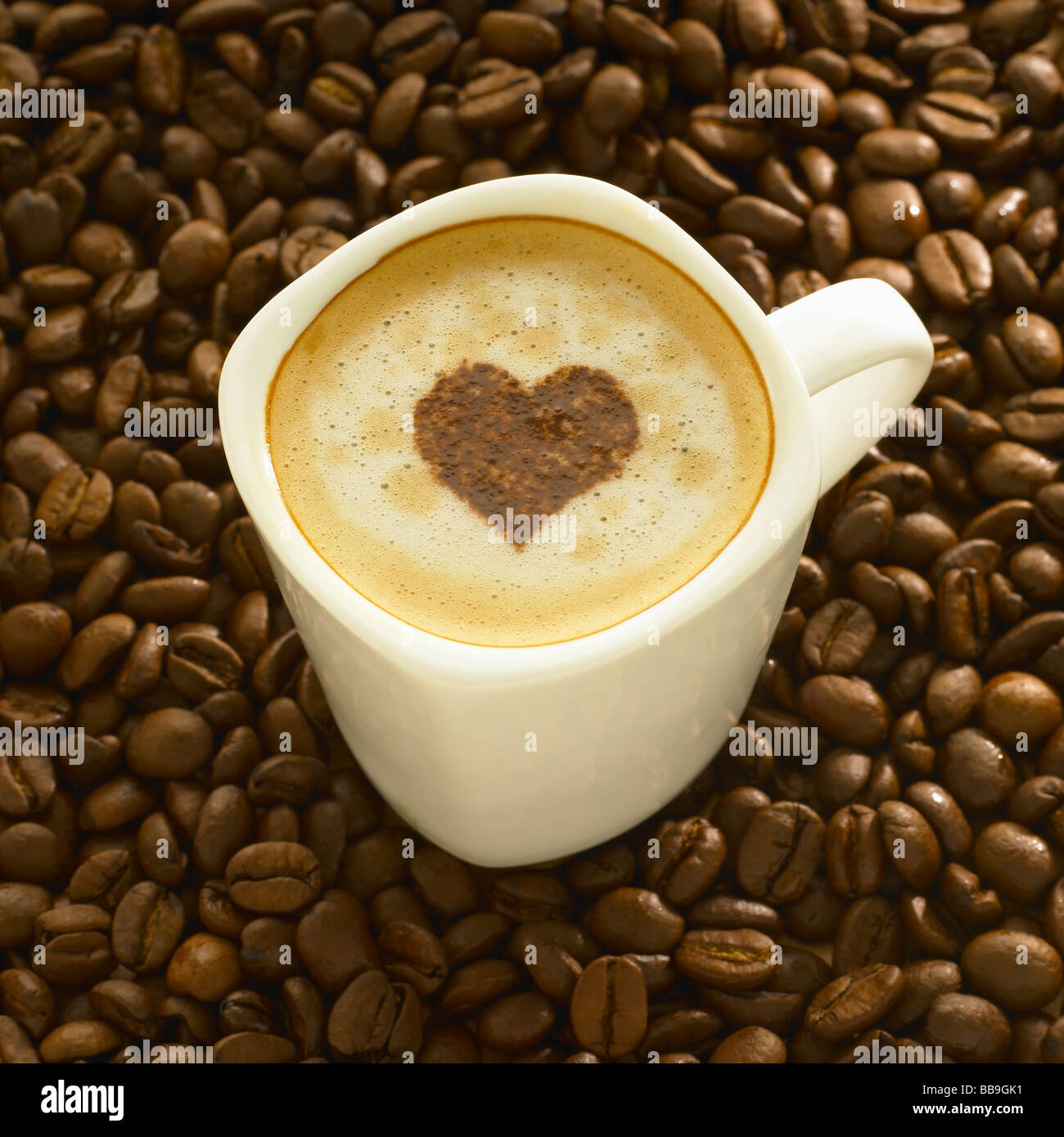 Taza de café con leche en forma de corazón, granos de café en la