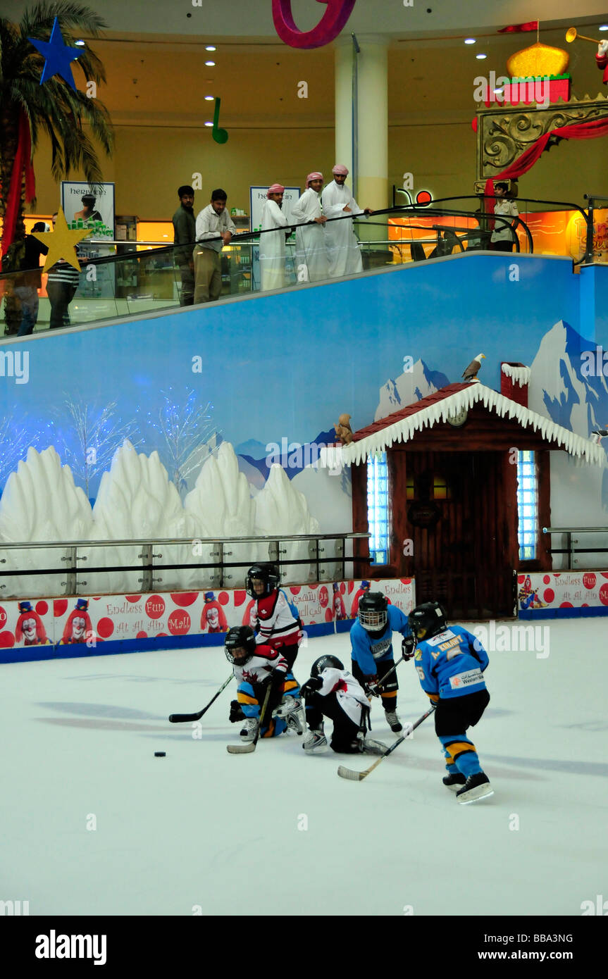 Los árabes en Dishdashas, las típicas vestiduras blancas, mirando a los niños jugar hockey sobre hielo en la pista de hielo del centro comercial Al Ain, Al Ain, un Foto de stock